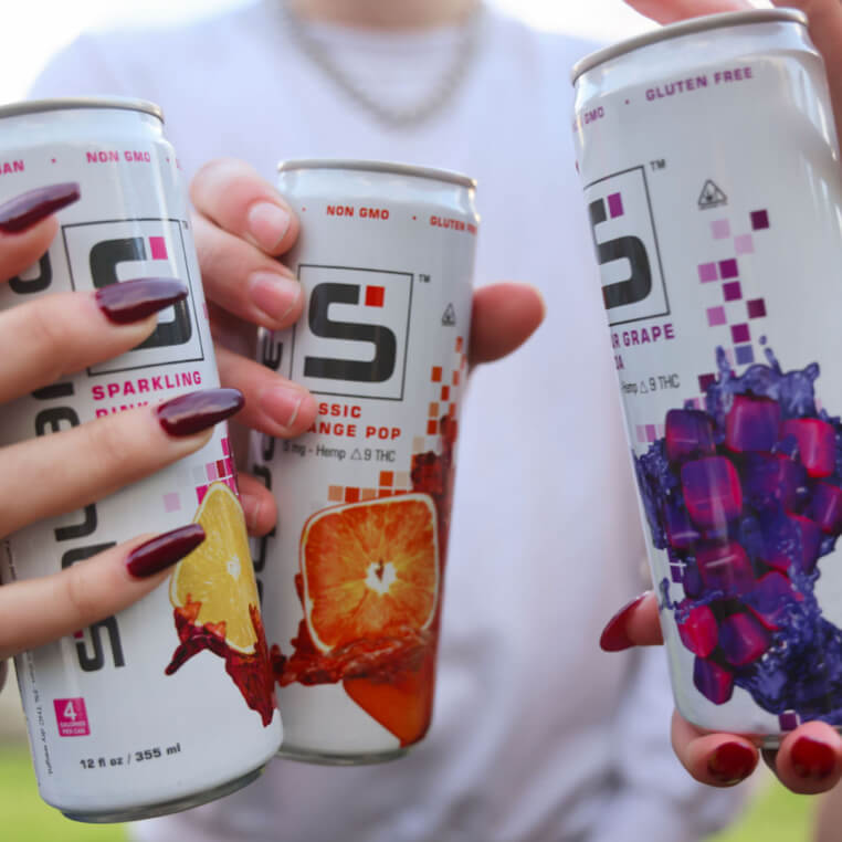 Three young adults holding 12 ounce cans of Squared up to cheers